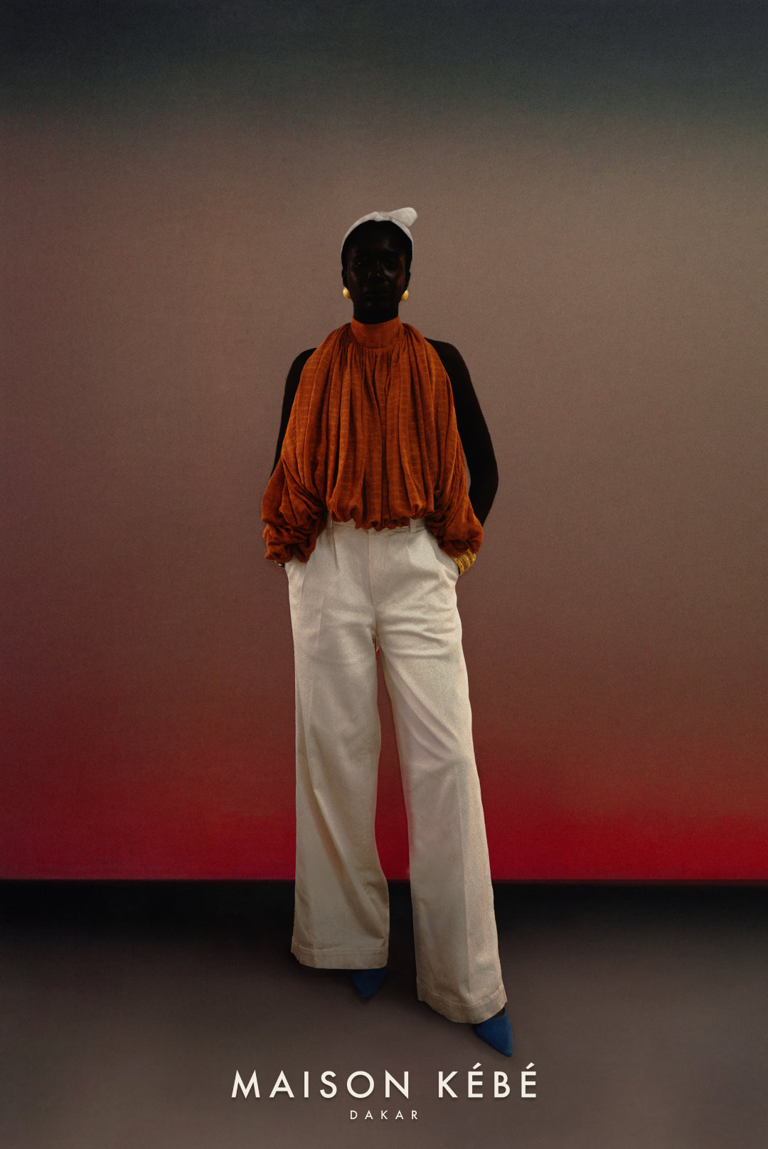Person wearing a rust-colored terra cotta  and white palazzo pants against a gradient wall with 'Maison Kebe' branding.